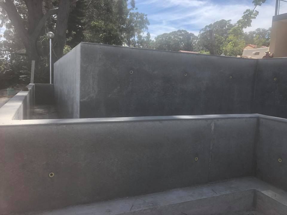 A Large Concrete Wall Is Surrounding A Swimming Pool — Luke Seears Concreting in Port Macquarie, NSW