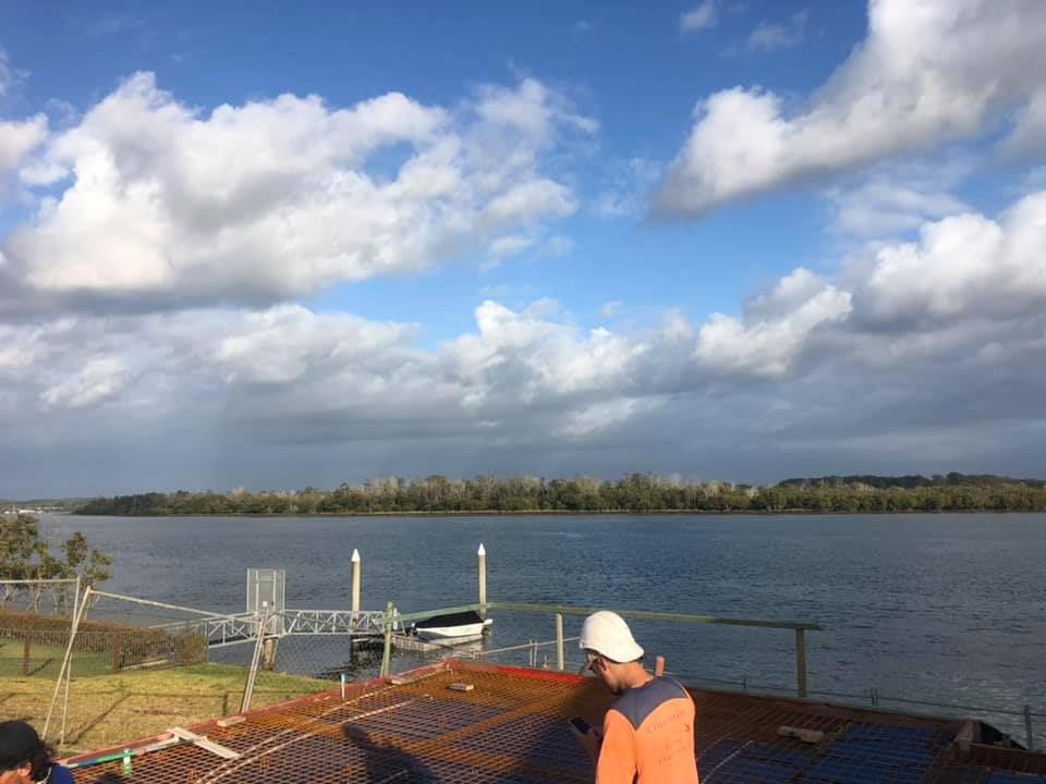 A Man Is Standing On A Roof Overlooking A Body Of Water — Luke Seears Concreting in Port Macquarie, NSW