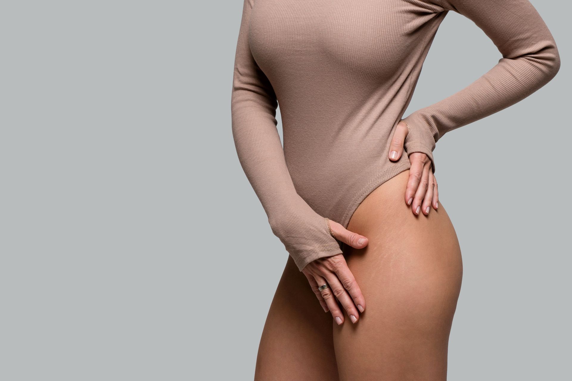 A woman in a bodysuit is holding her hand on her hip.