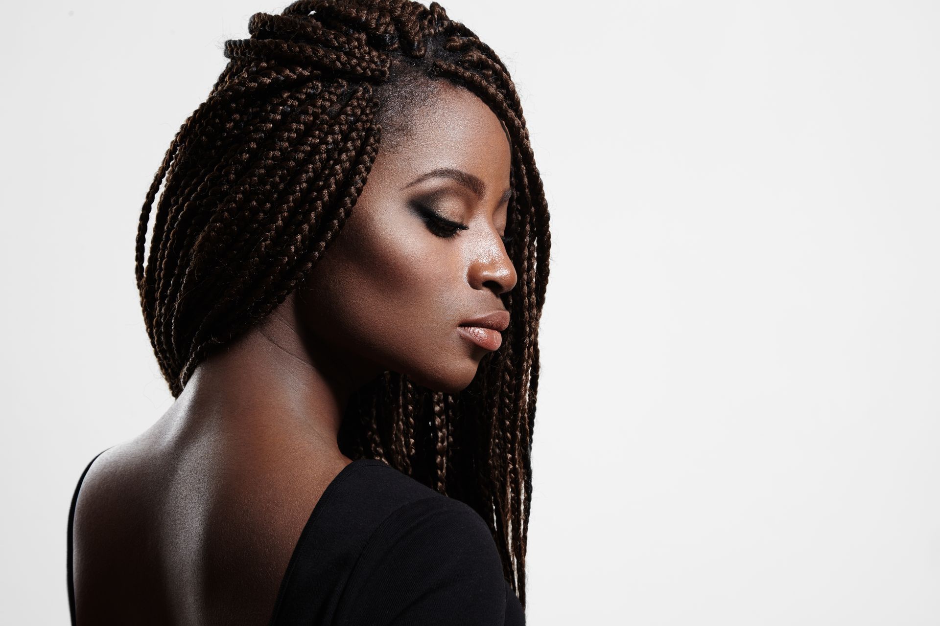 A woman with braids is wearing a black shirt and looking down.