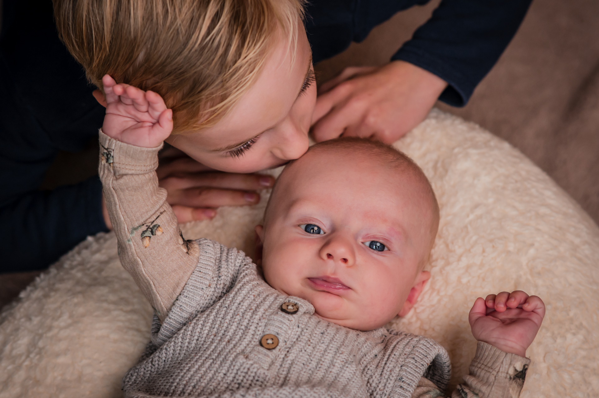 Een jongen kust een baby op de wang.