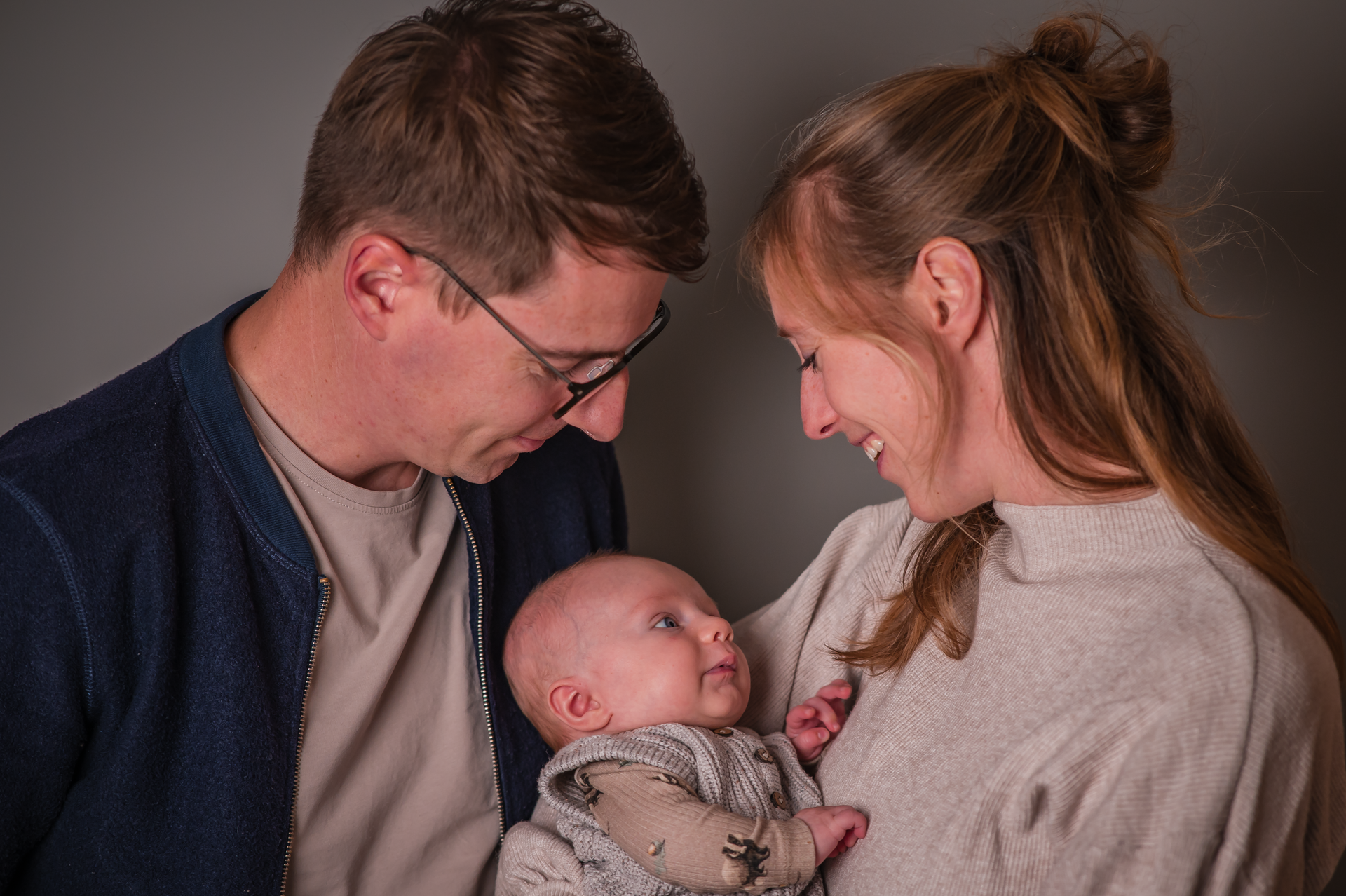 Een man en een vrouw houden een baby in hun armen.