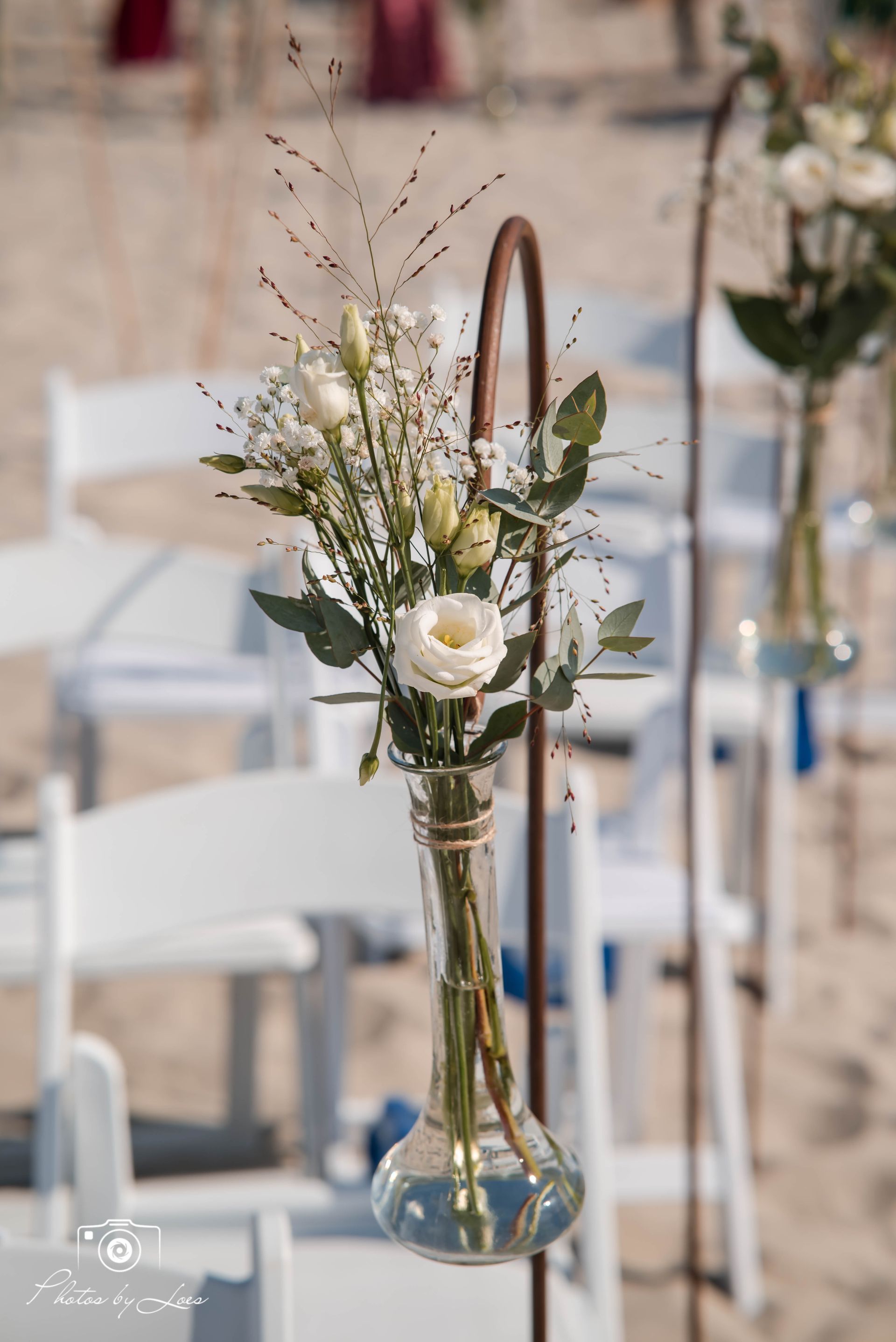 Een vaas gevuld met bloemen hangt aan een paal.