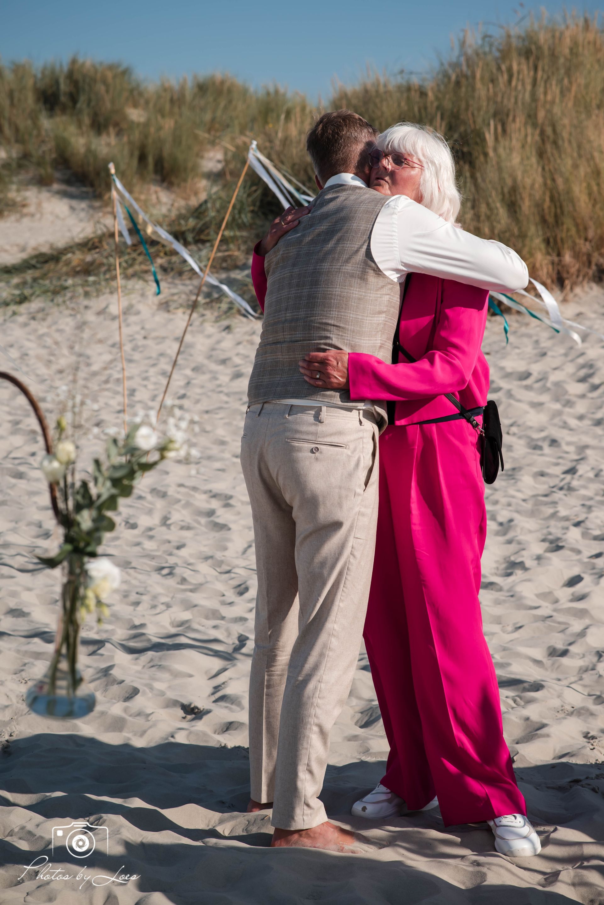 Een man en een vrouw omhelzen elkaar op het strand.