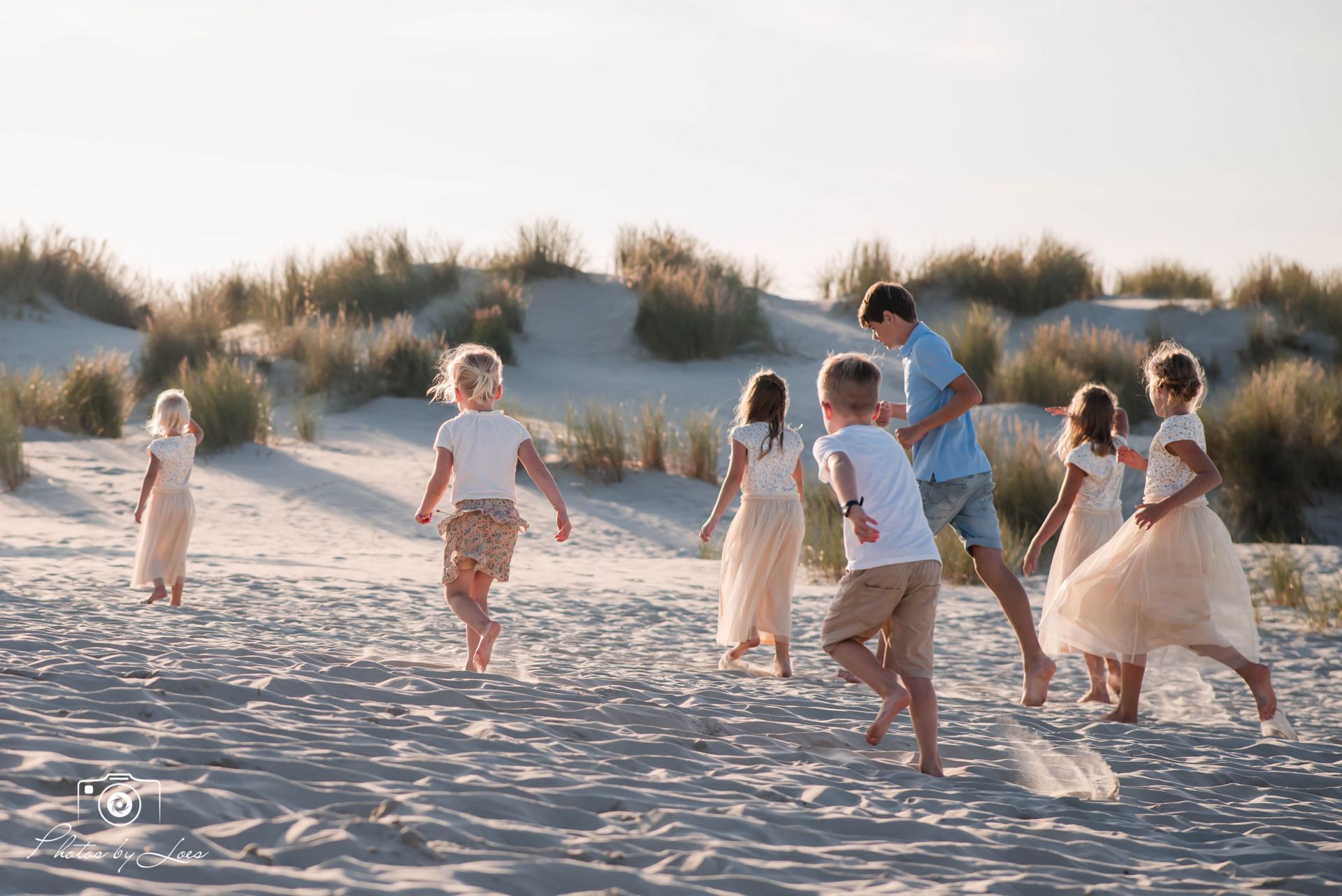 Een groep kinderen speelt op een zandstrand.
