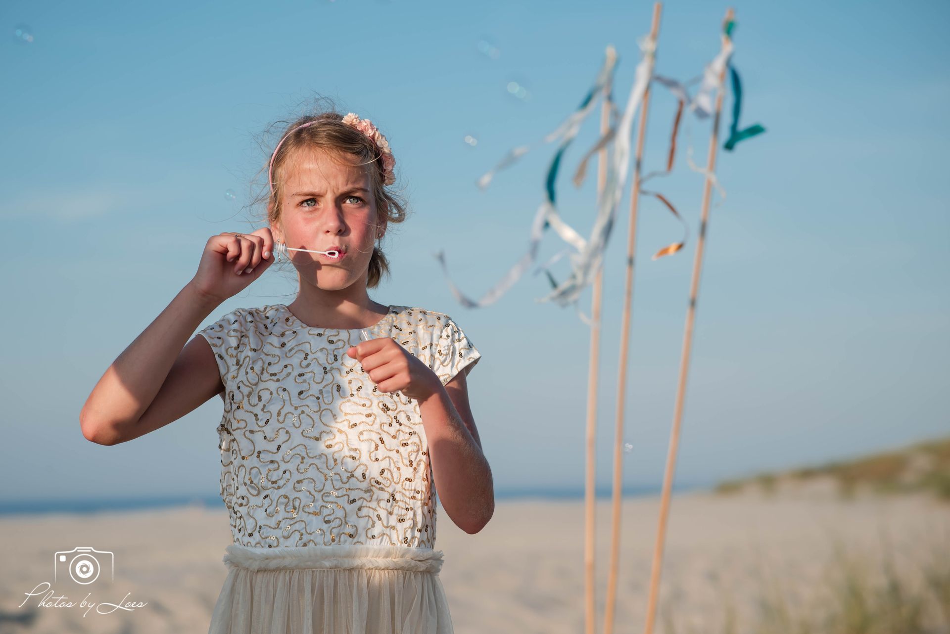 Een jong meisje blaast zeepbellen op het strand.