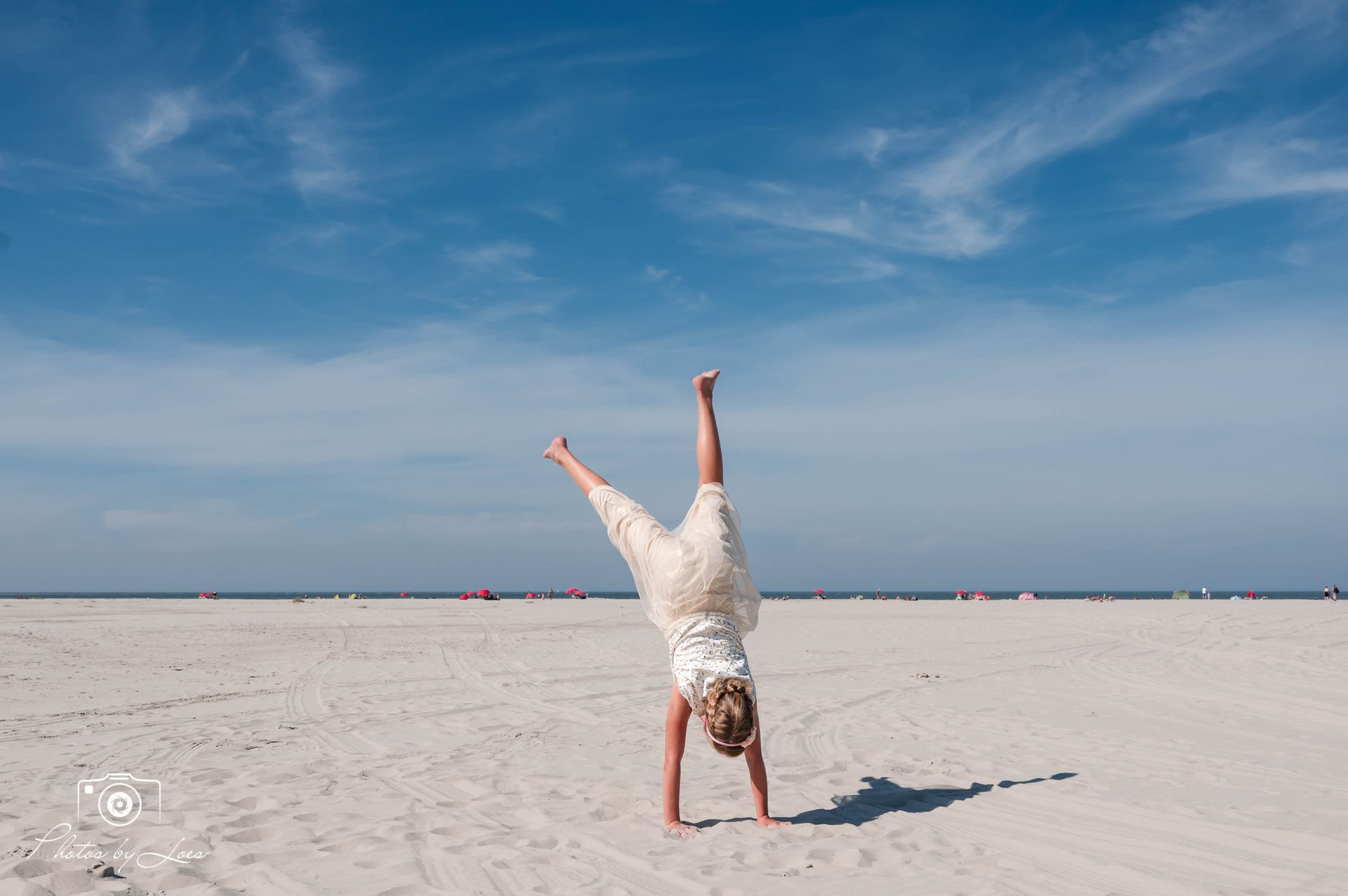 Een vrouw doet een handstand op het strand.
