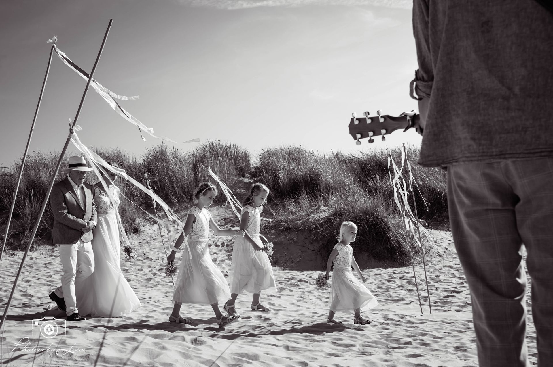 Een zwart-witfoto van een groep mensen die op het strand loopt.