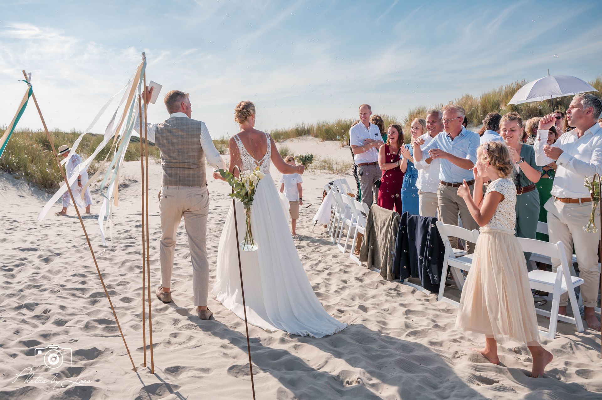 Een bruid en bruidegom lopen naar het altaar tijdens hun strandbruiloft.