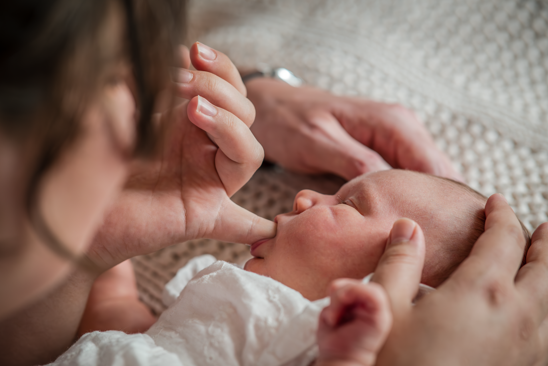 Een vrouw steekt haar vinger in de mond van een baby.