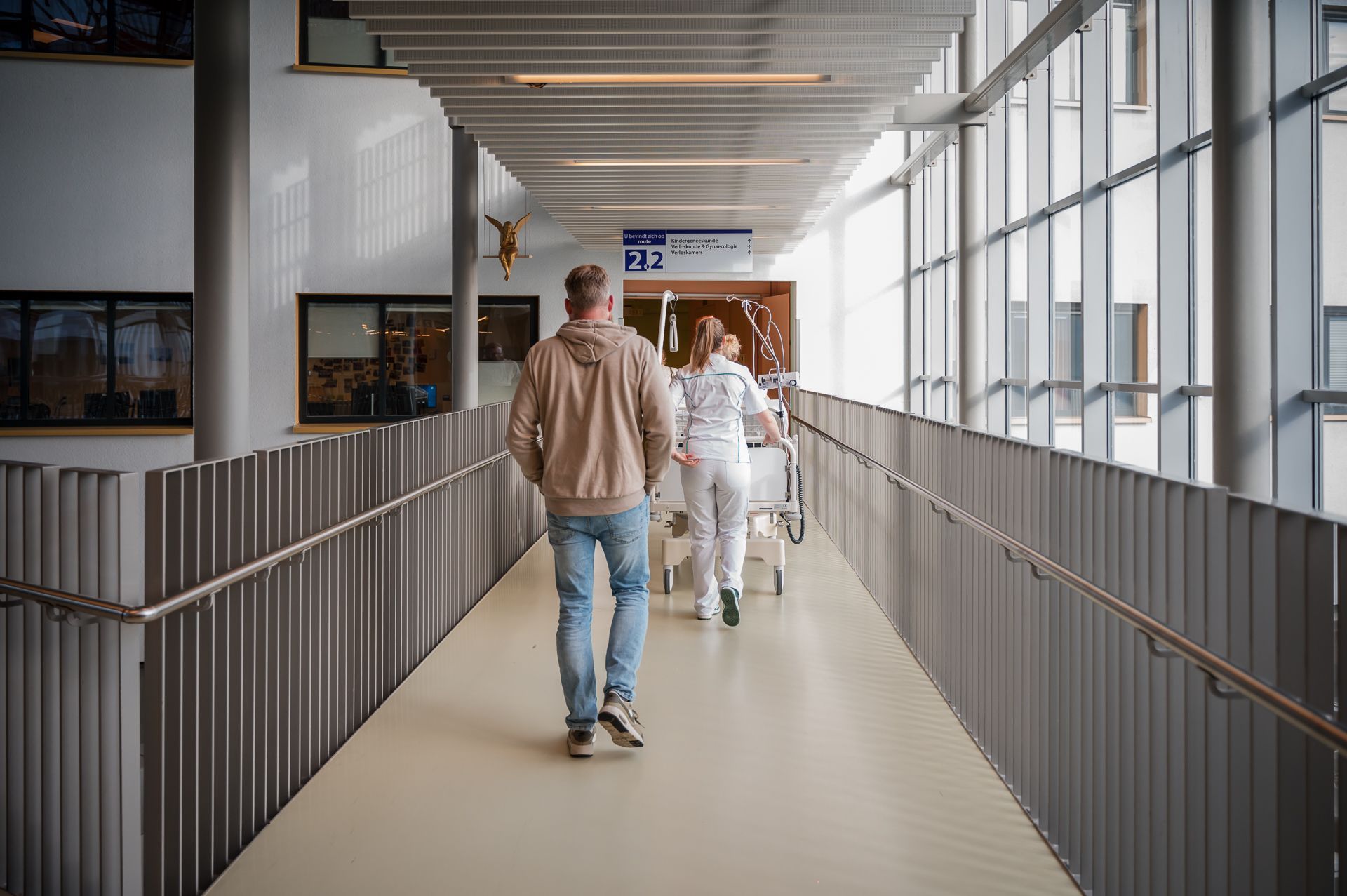 Een man en een verpleegster lopen door een ziekenhuisgang.