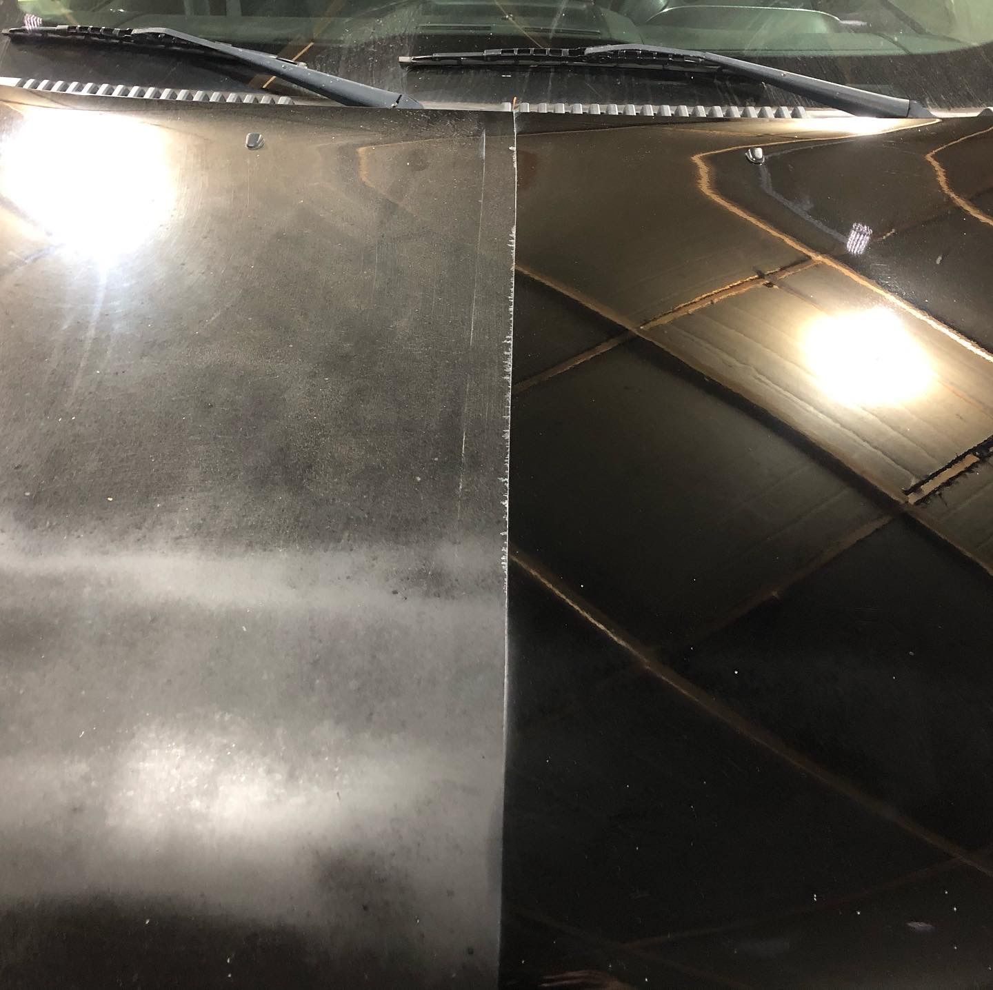A close up of a black car hood and windshield