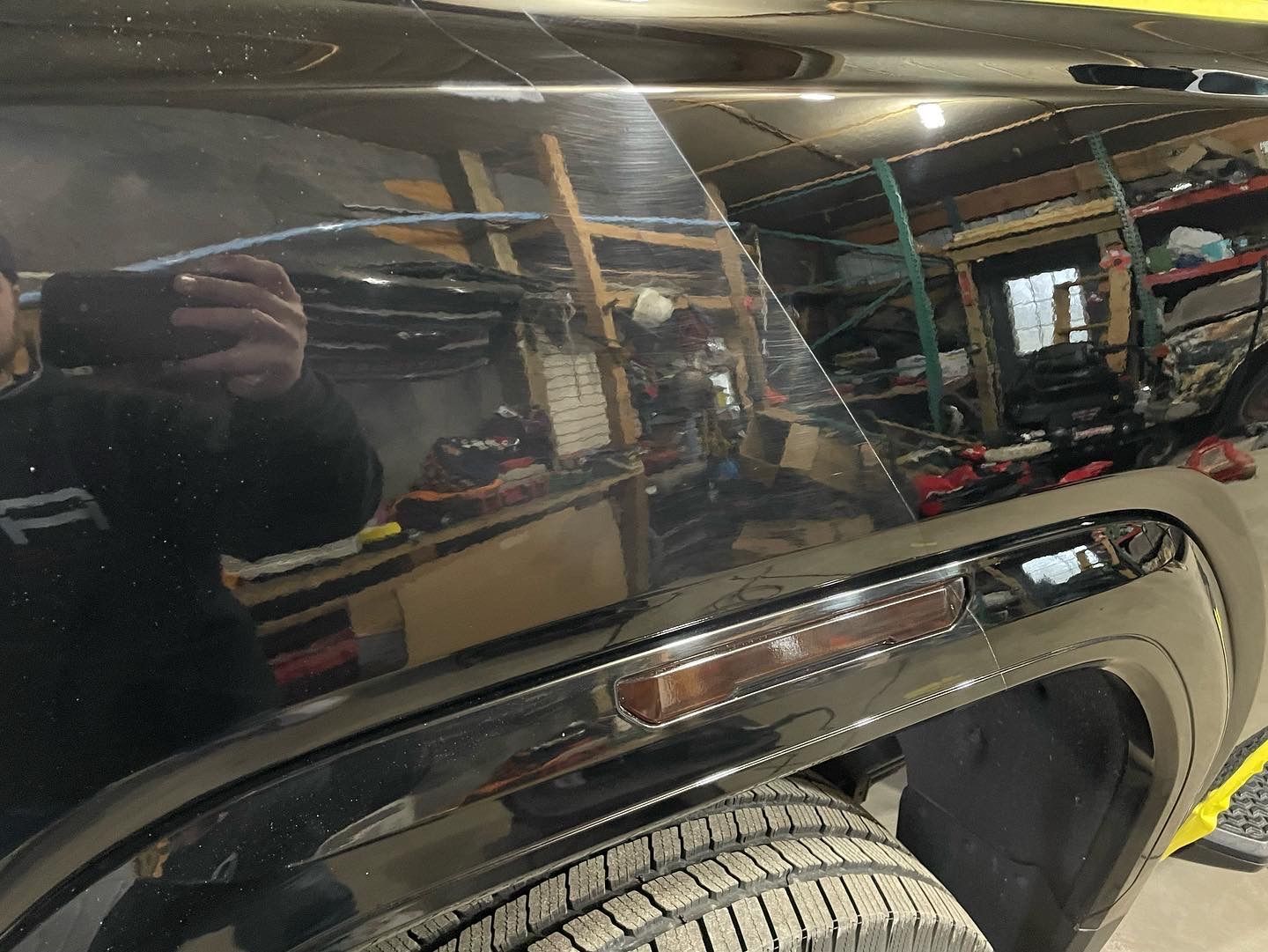 A man is taking a picture of his reflection in the side of a car.