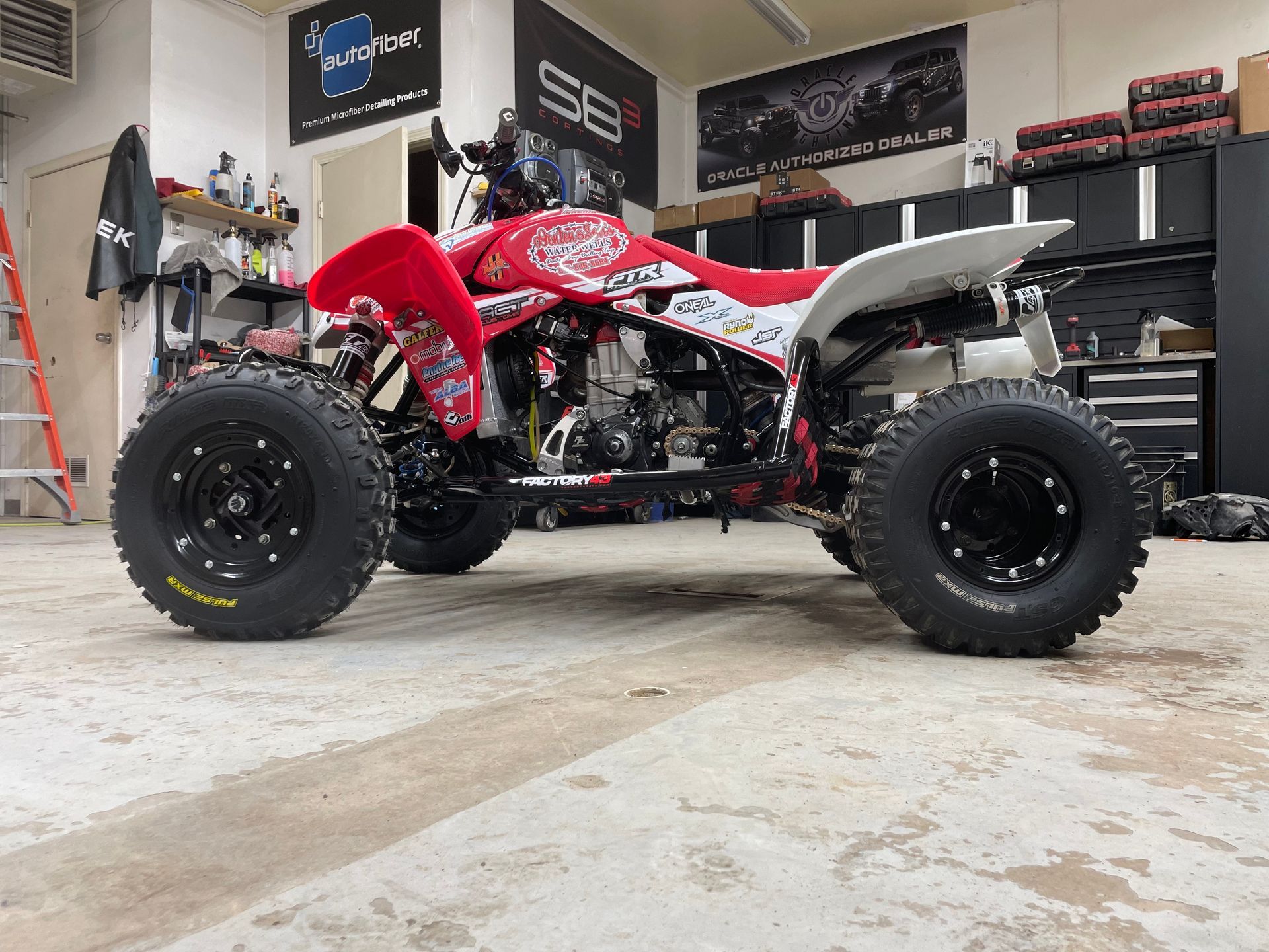 A red and white atv is parked in a garage.