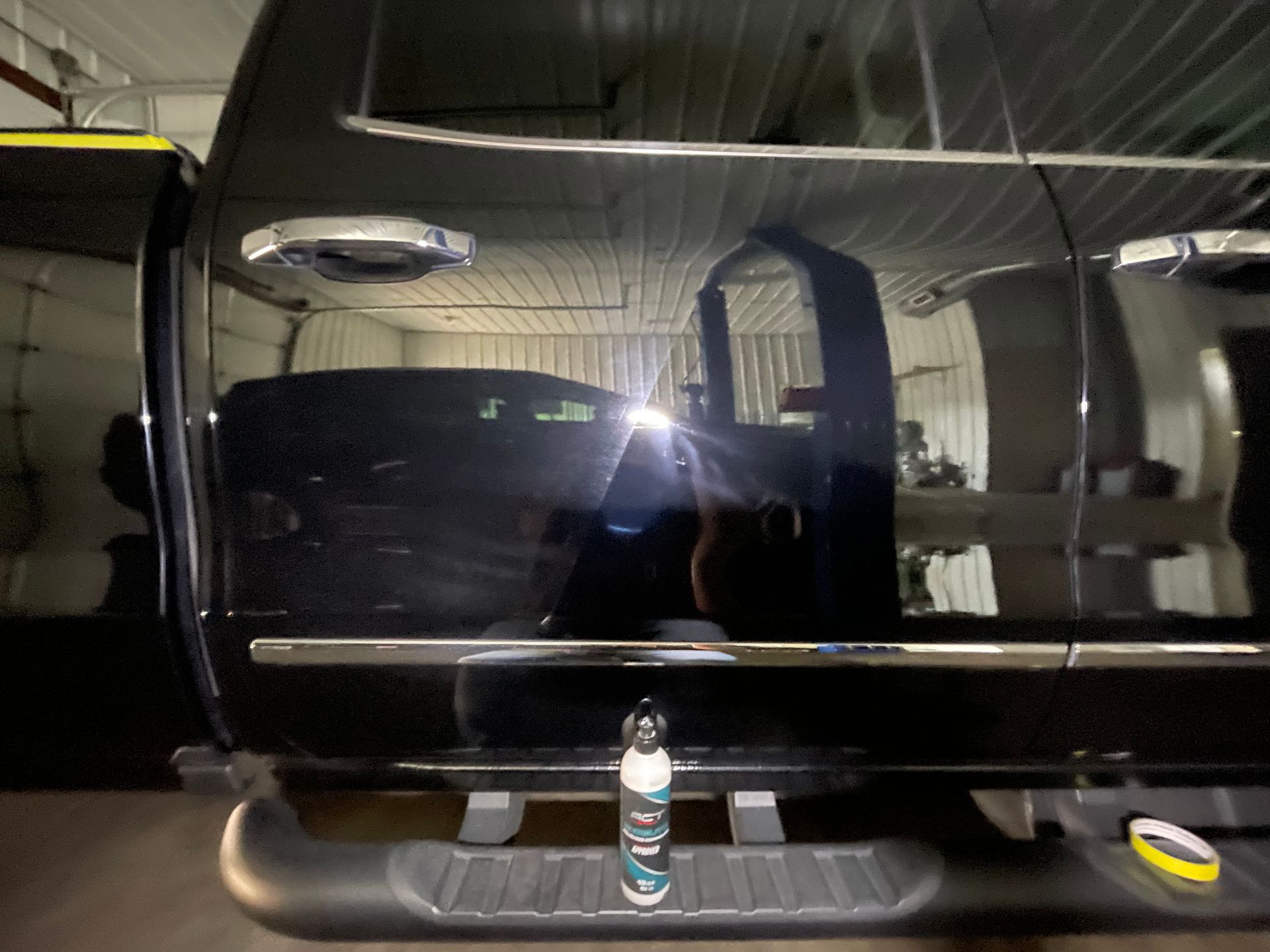 A black truck is parked in a garage with the door open