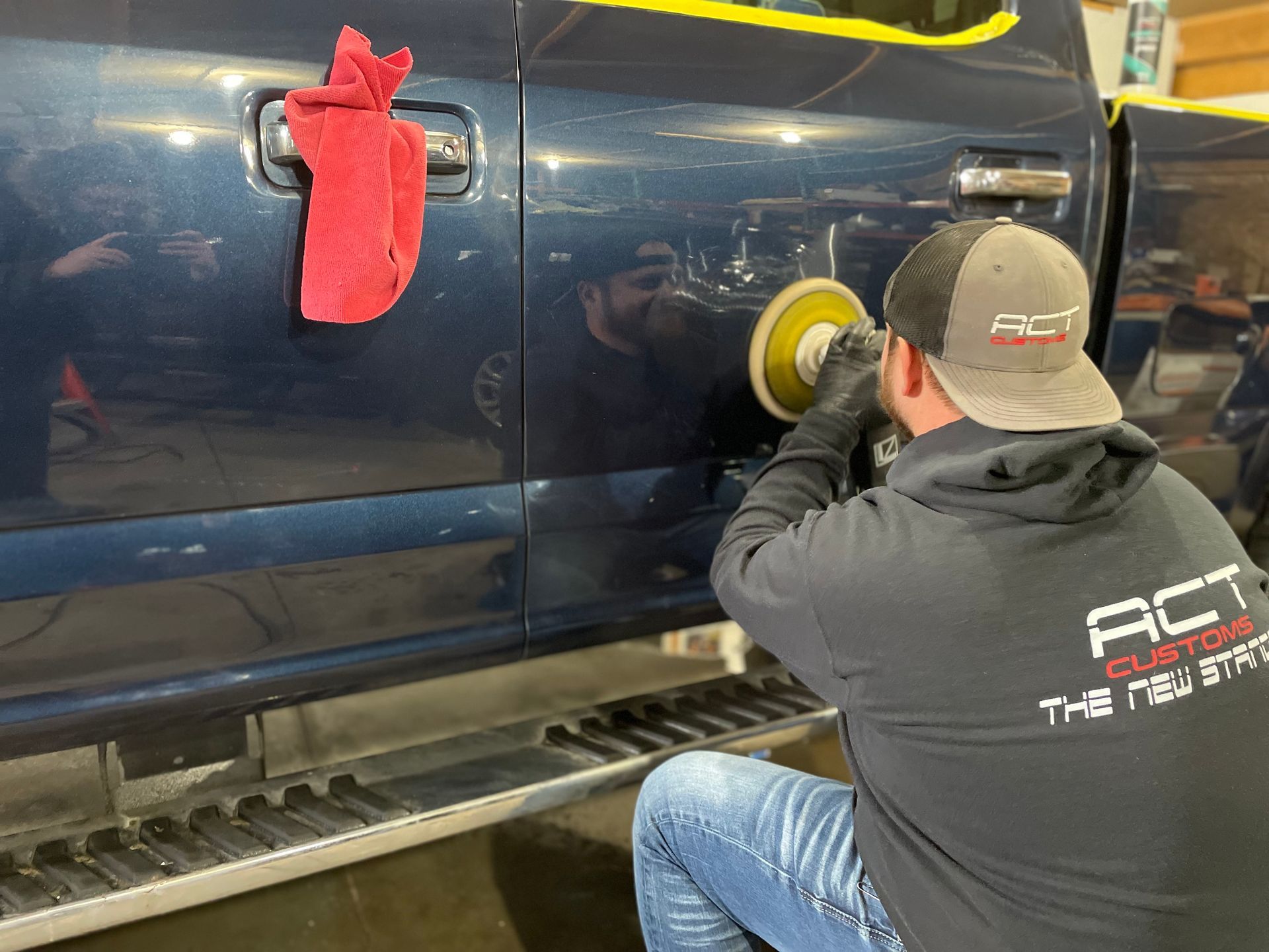 A man is polishing the side of a truck.
