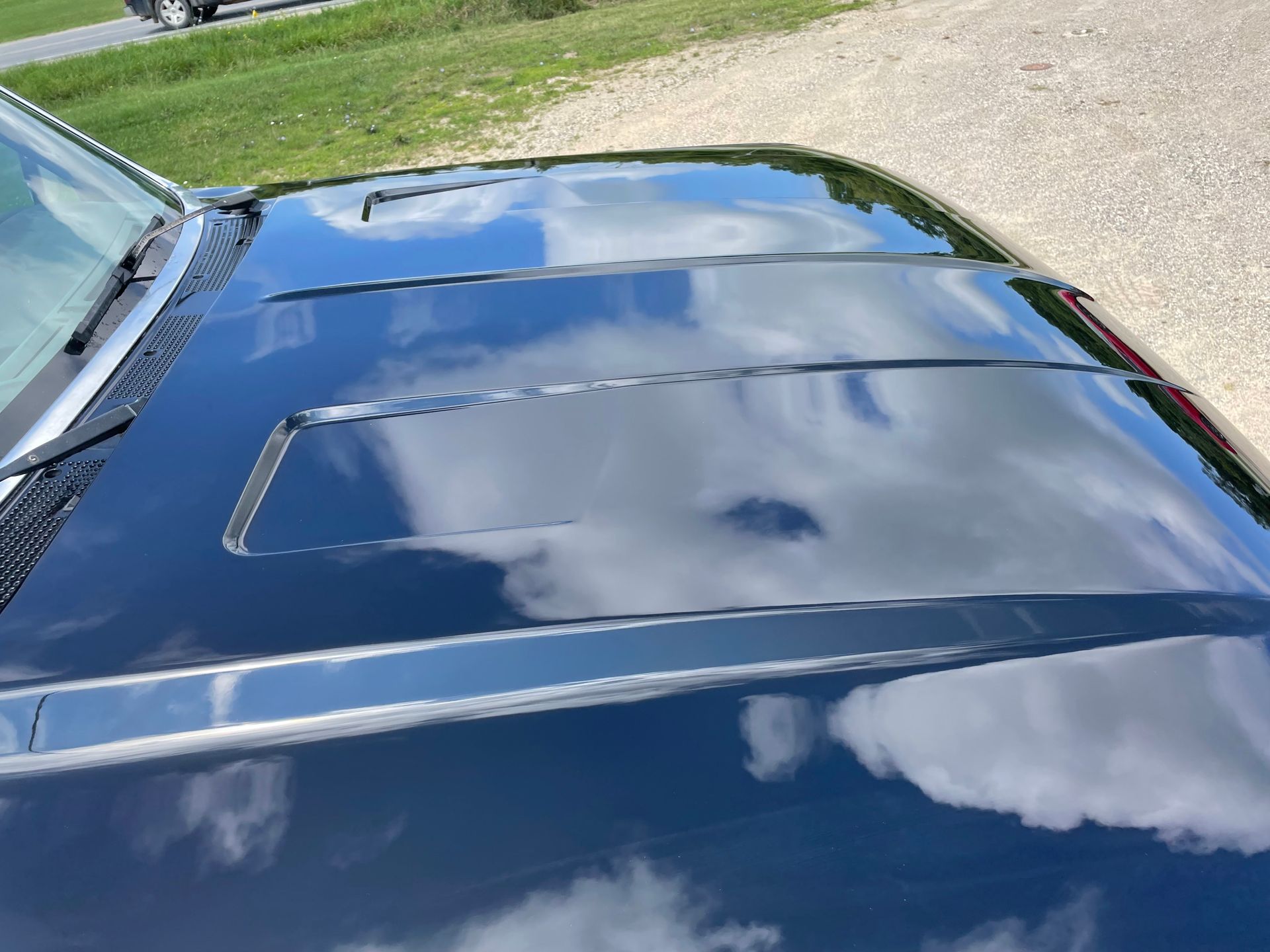 The hood of a black car is shiny and reflects the sky