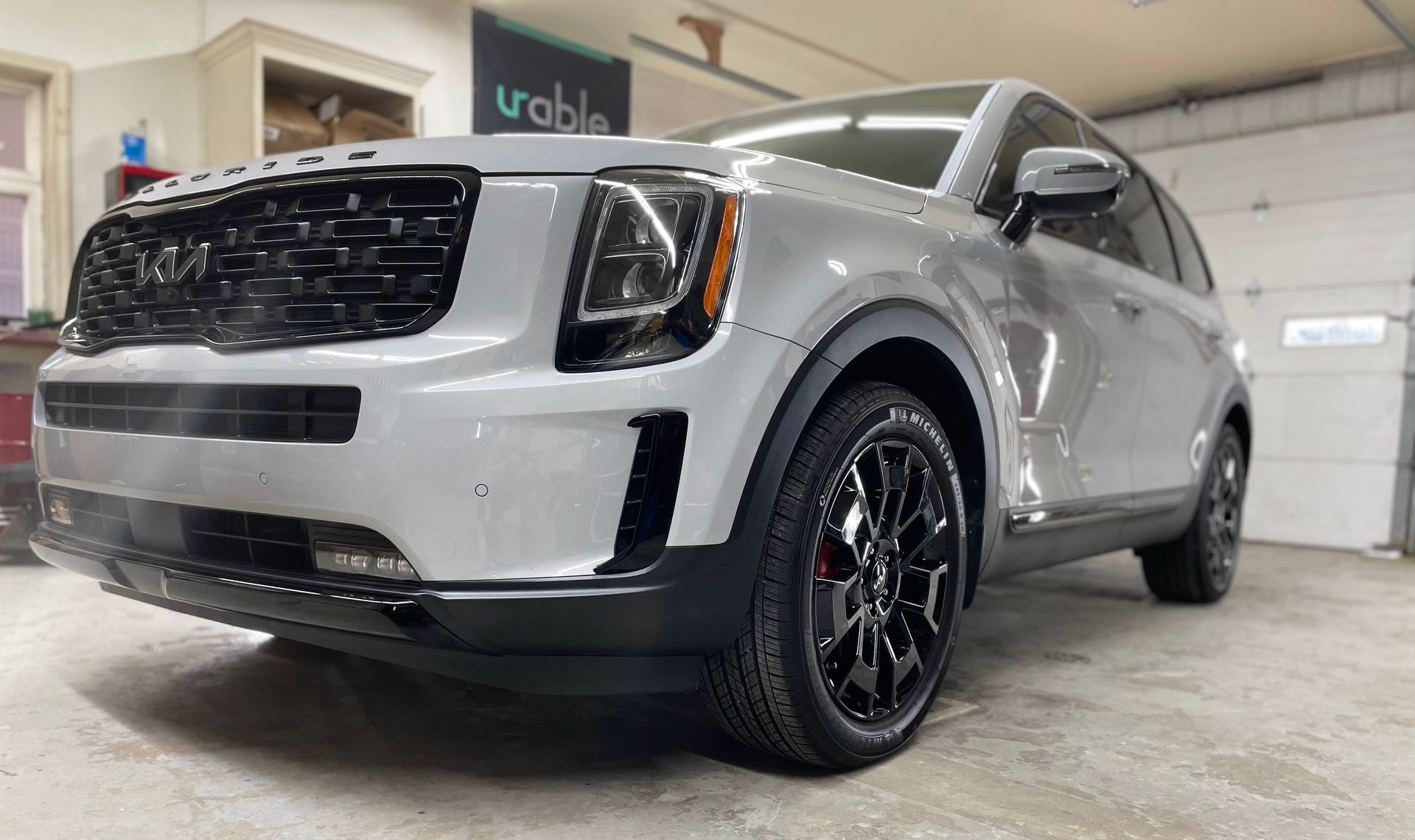 A silver suv is parked in a garage next to a garage door.
