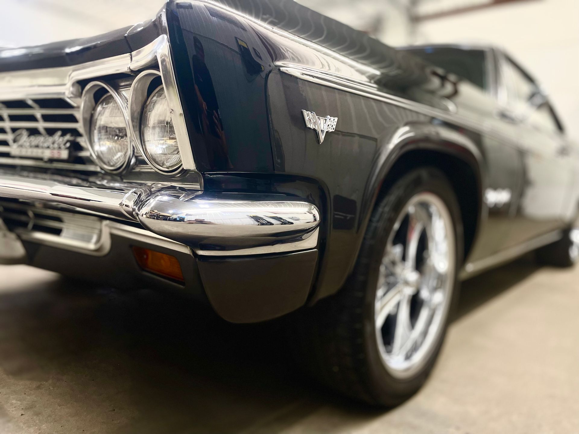 A black chevrolet impala is parked in a garage.