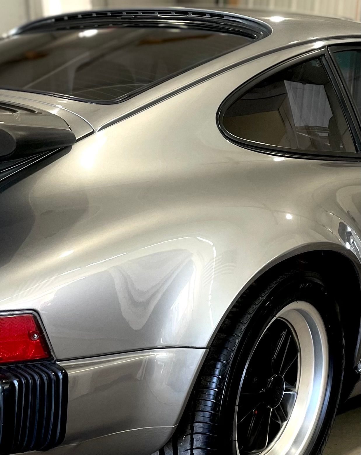 A silver porsche 911 turbo is parked in a garage