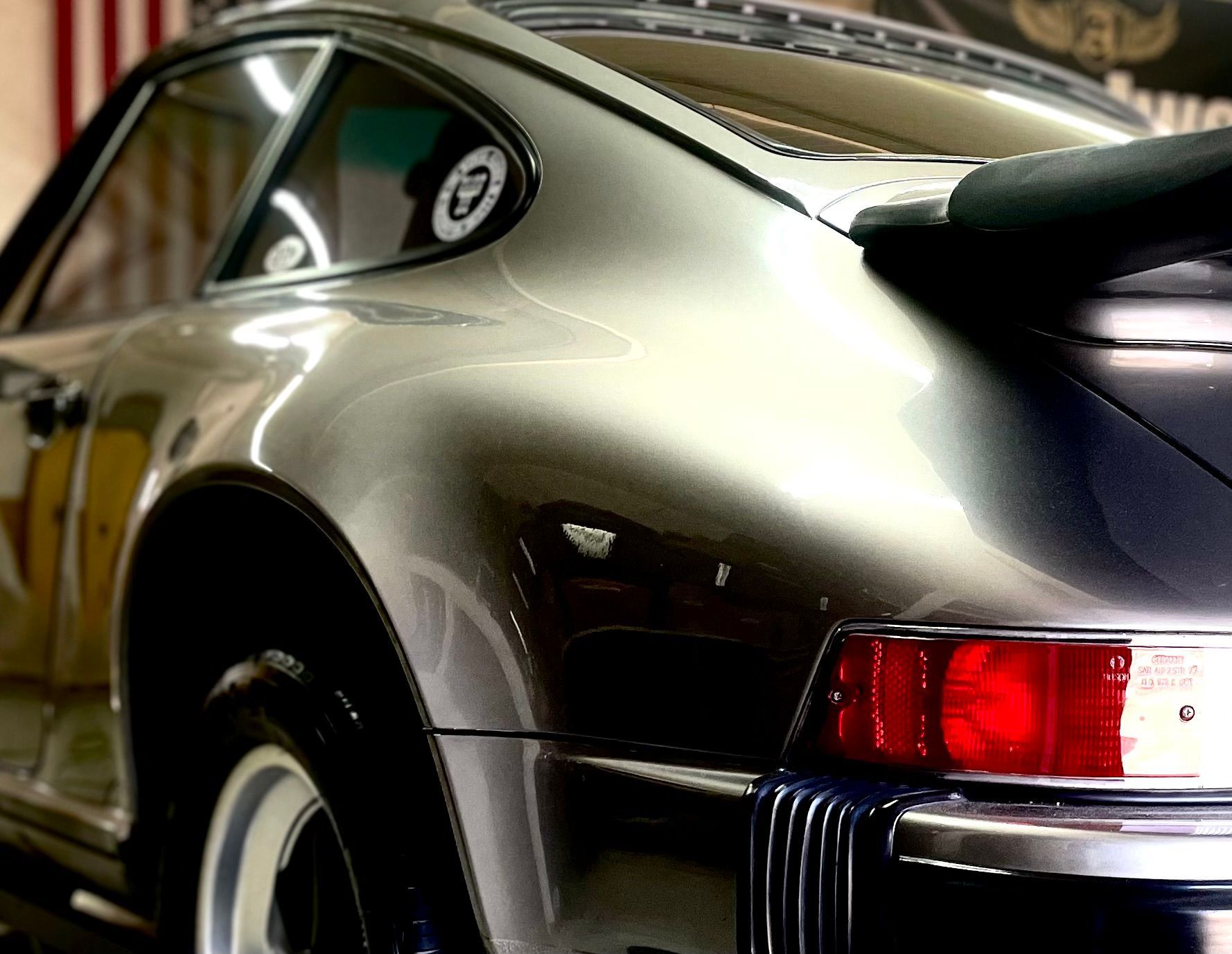 A silver porsche is parked in front of an american flag