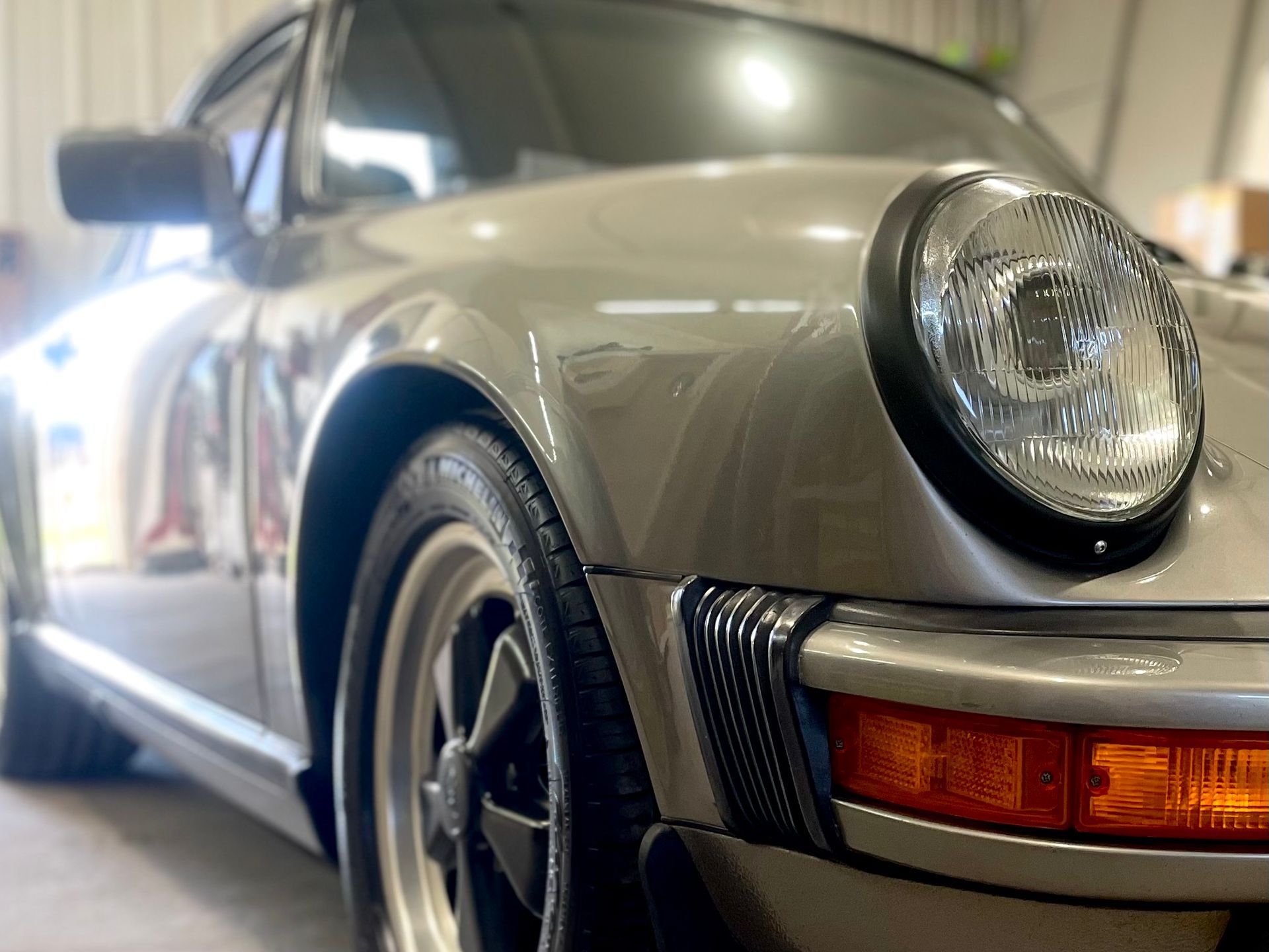 A silver porsche 911 is parked in a garage.