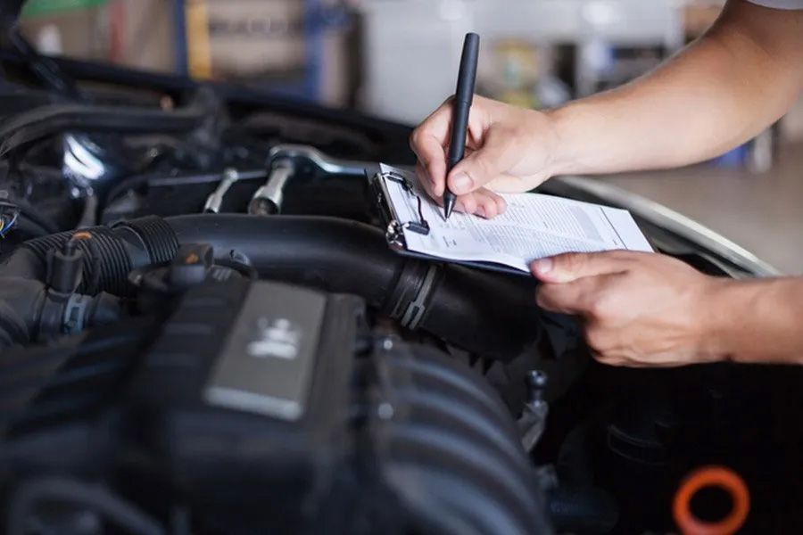 A Person is Writing on a Clipboard Under the Hood of a Car — Toowoomba Lube & Mechanical in Glenvale, QLD