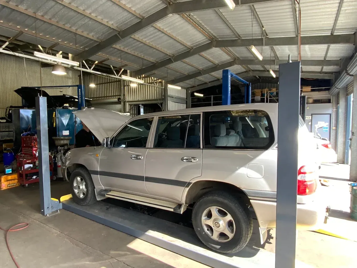 A Silver Suv is Parked on a Lift in a Garage — Toowoomba Lube & Mechanical in Glenvale, QLD