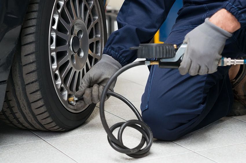 A Man is Kneeling Down and Pumping Air Into a Tire — Toowoomba Lube & Mechanical in Glenvale, QLD