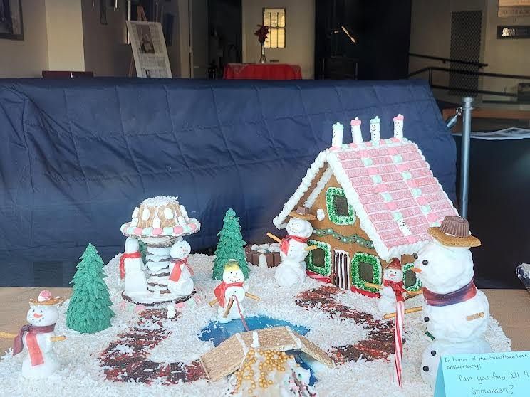 Snowman-themed gingerbread house display with candy decorations on a tabletop