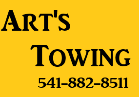 Yellow sign for Art's Towing with phone number 541-882-8511