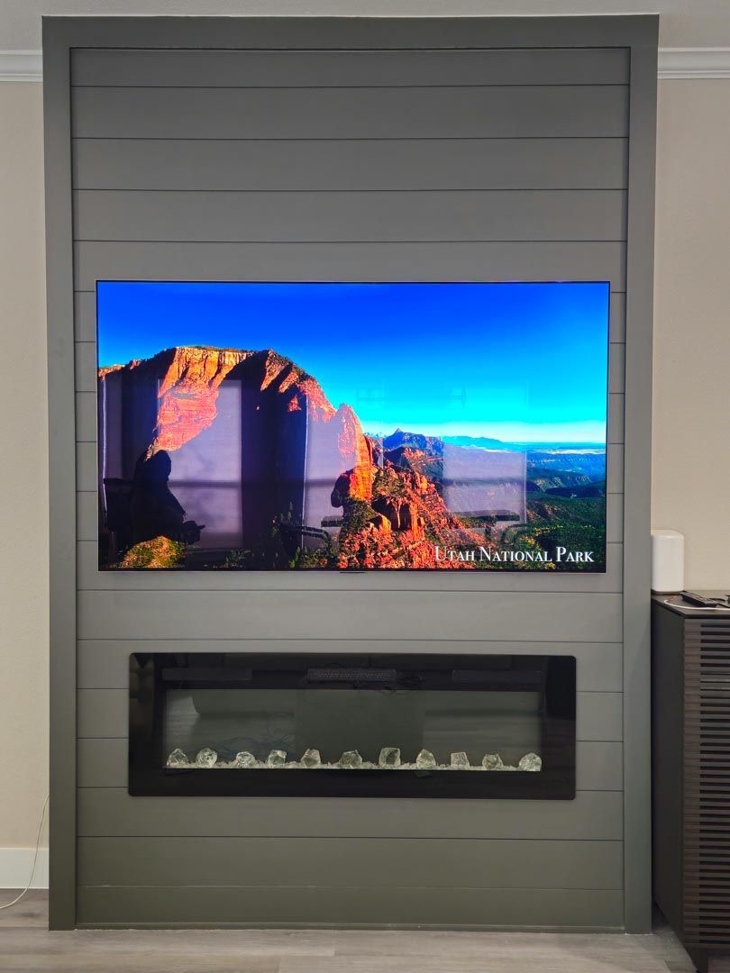Modern living room fireplace with a wall-mounted TV displaying a desert landscape