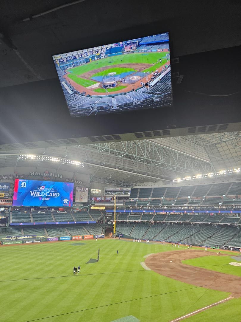 Empty baseball stadium with green field and giant scoreboard showing the field view