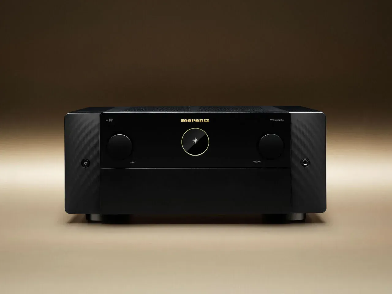 Black stereo receiver with central dial and two side knobs on a beige background