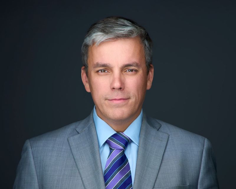 A man in a suit and tie is looking at the camera.