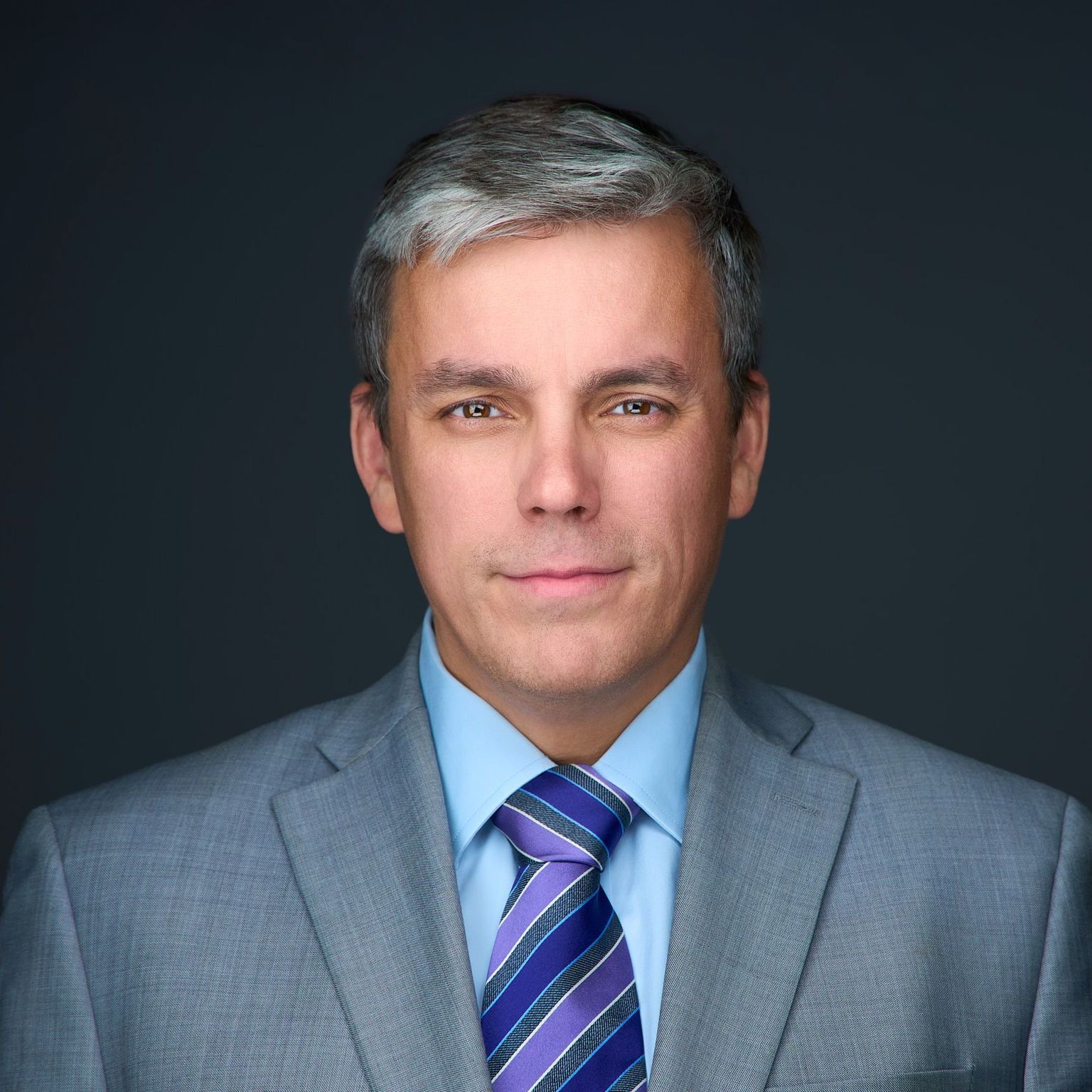A man in a suit and tie is smiling for the camera.