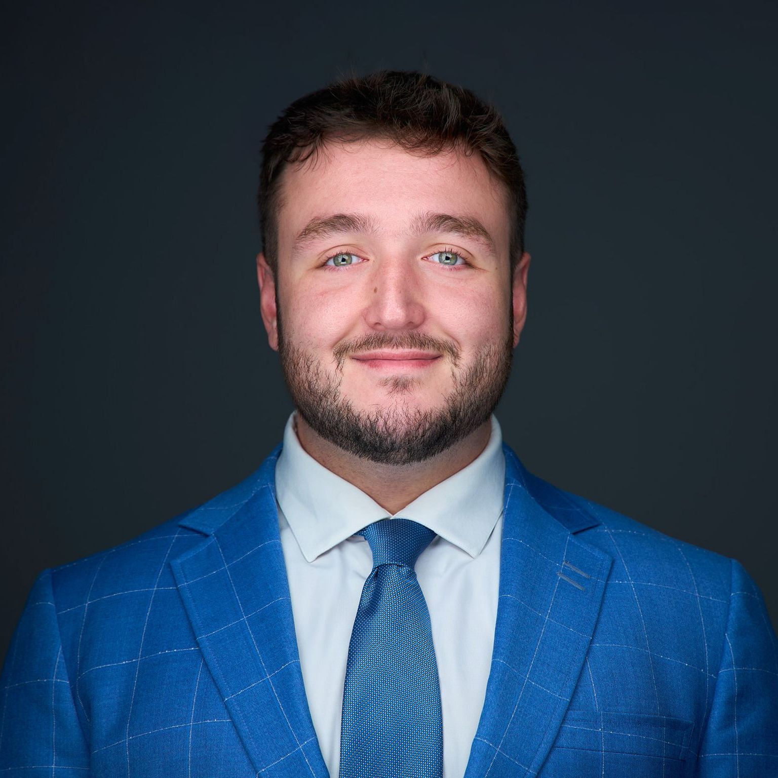 A man with a beard is wearing a blue suit and tie.