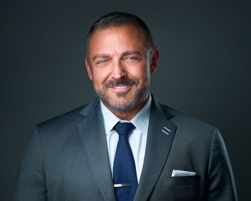 A man in a suit and tie is smiling for the camera.