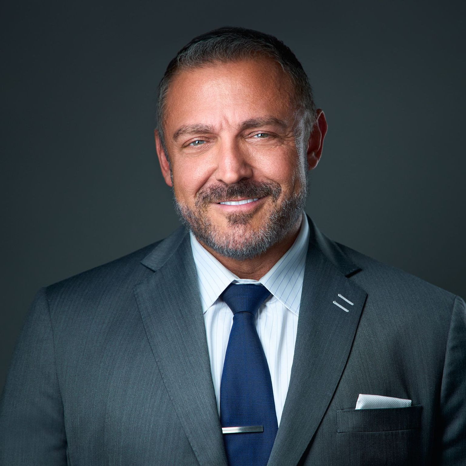 A man in a suit and tie is smiling for the camera.