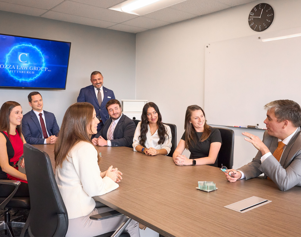 A group of people are posing for a picture while sitting around a table.