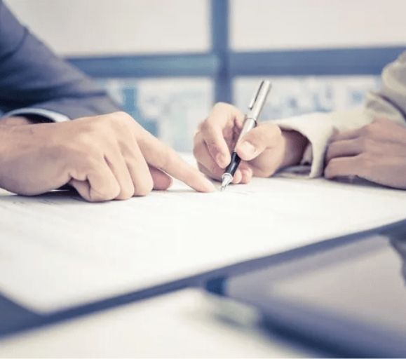 Two people are sitting at a table writing on a piece of paper.
