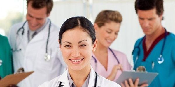 A group of doctors and nurses are smiling for the camera