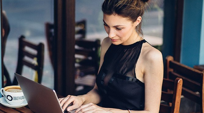 A woman is sitting at a table using a laptop computer.