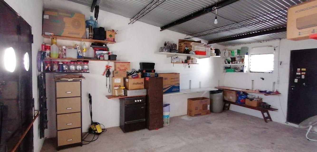 Interior de un garaje desordenado con estantes llenos de objetos y una ventana.