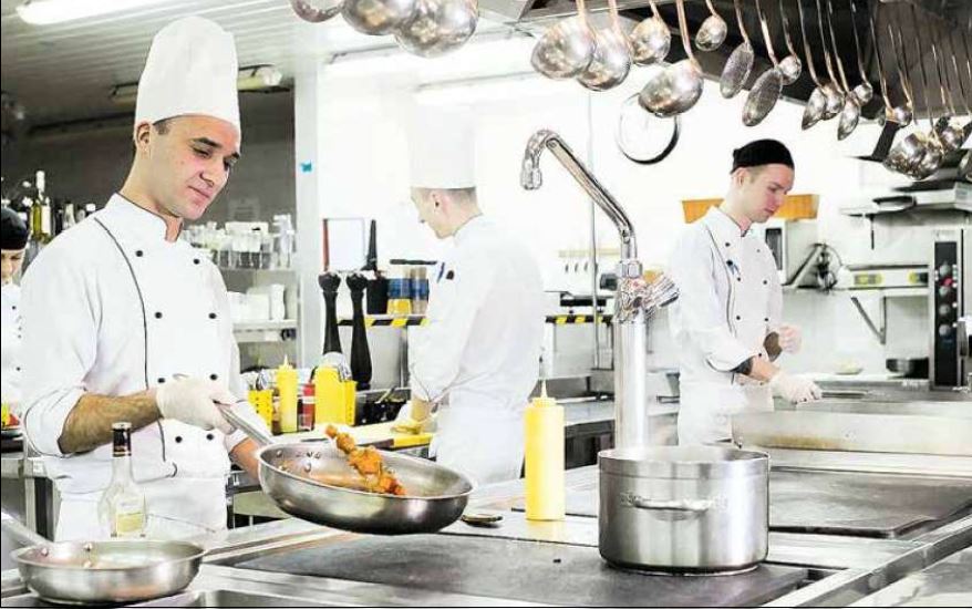 Eine Gruppe Köche bereitet in einer Küche Essen zu.
