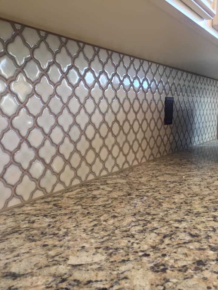 Patterned kitchen backsplash and speckled granite countertop beneath a slanted wall.