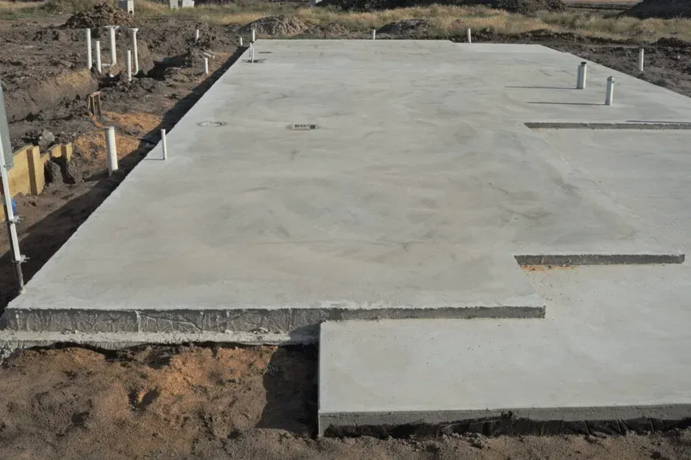Fresh concrete slab foundation under construction on a dirt site