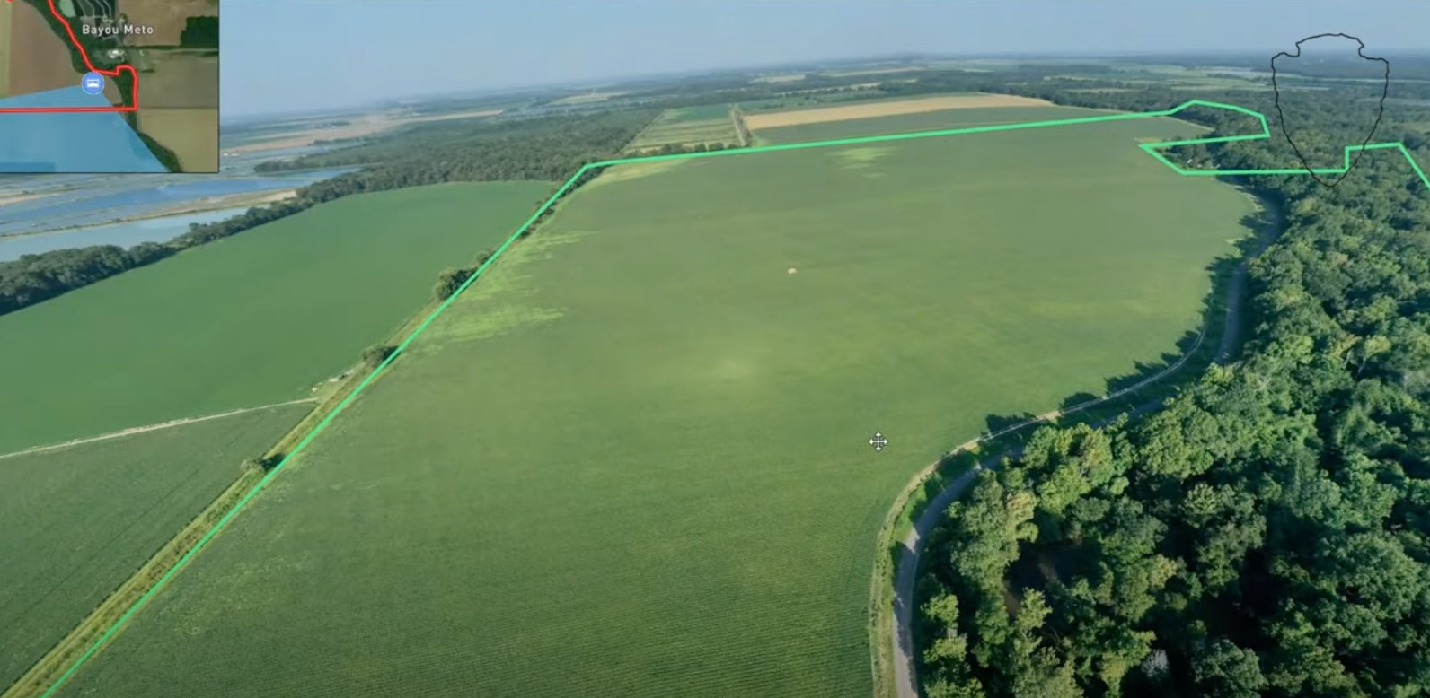 An aerial view of a field surrounded by trees and a river.