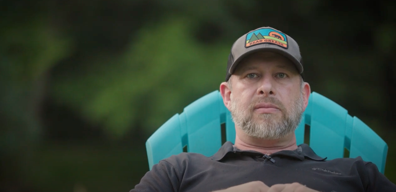 A man with a beard is sitting in a blue chair.