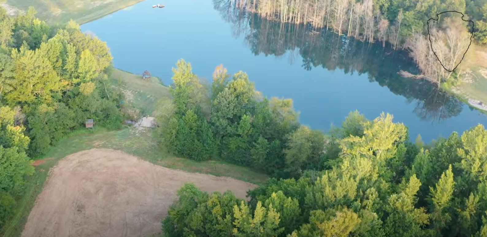 An aerial view of a lake surrounded by trees and grass.